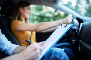 close up view driving instructor holding checklist while background female student steering driving car 342744 688